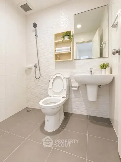 Modern bathroom with sleek fixtures and minimalist design, featuring a wall-mounted sink and open shower.