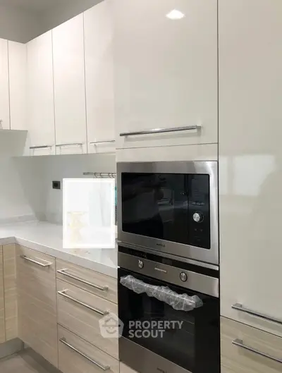 Modern kitchen with sleek cabinetry and built-in oven, showcasing contemporary design and functionality.