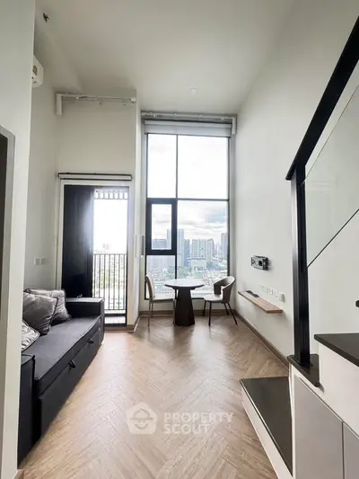 Modern living room with high ceiling and city view, featuring sleek furniture and large windows.