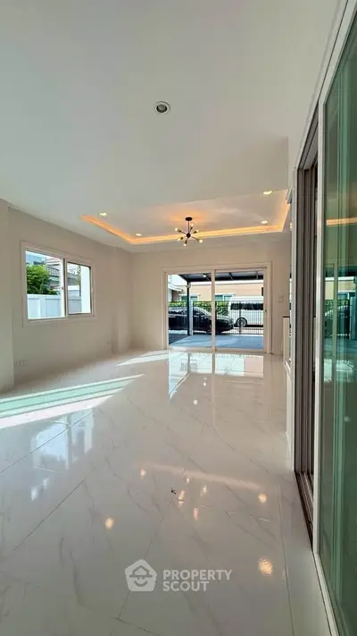 Spacious modern living room with glossy marble floors and large windows for natural light.