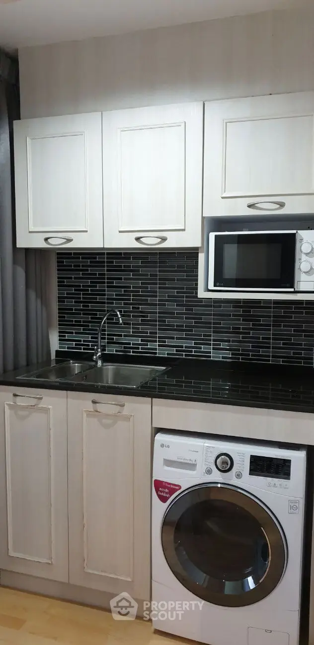 Modern kitchen with sleek cabinetry, black backsplash, and built-in appliances.