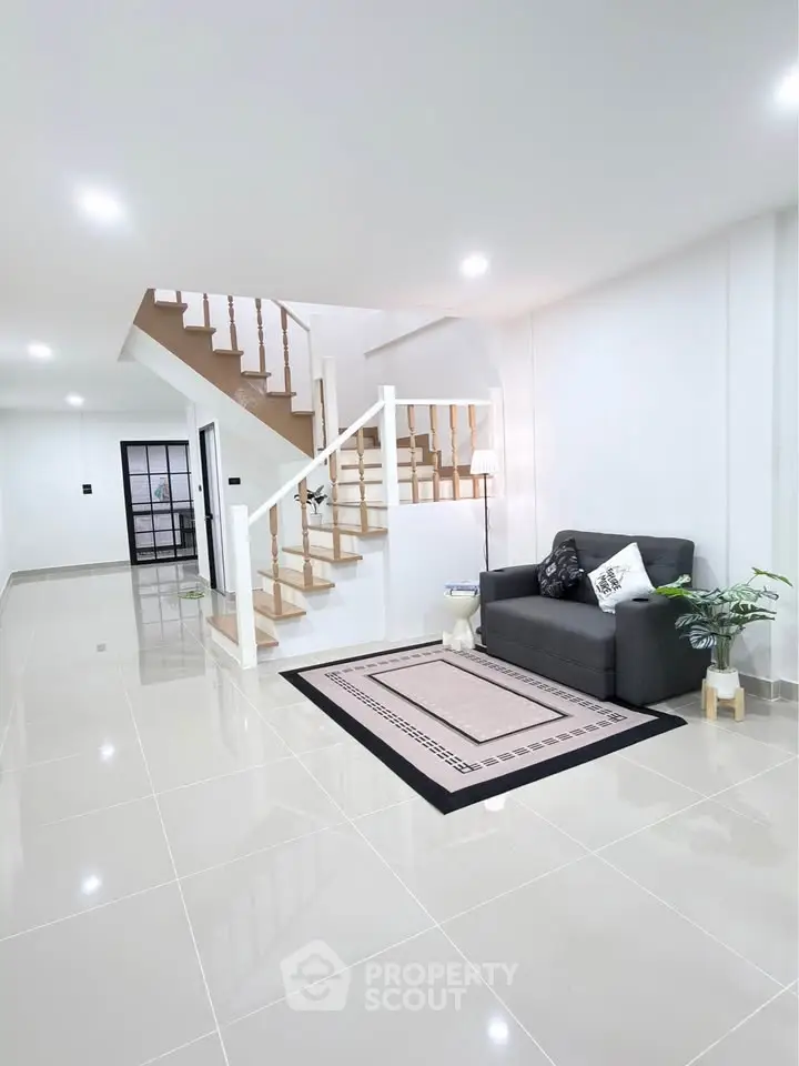 Spacious modern living room with sleek staircase and cozy seating area, perfect for stylish living.