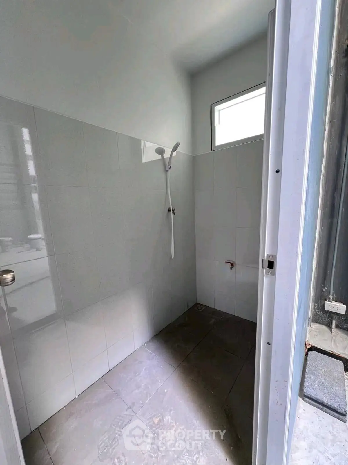 Minimalist bathroom with showerhead and window, ideal for compact living spaces.