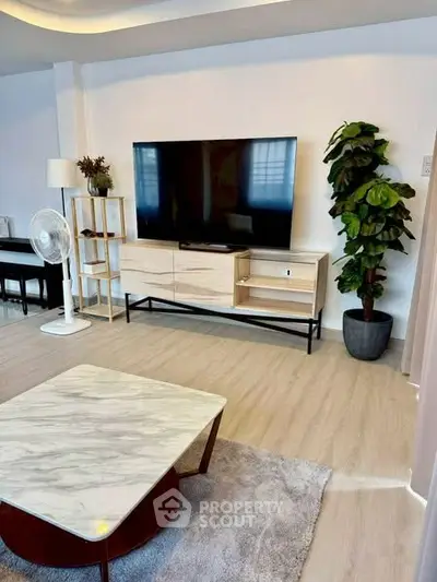 Modern living room with large TV, stylish furniture, and elegant decor.