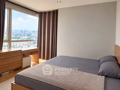 Spacious bedroom with city view and modern furnishings in high-rise apartment.