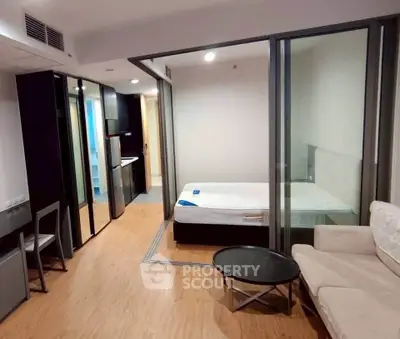 Modern studio apartment with open layout, featuring a cozy living area and bedroom with glass partition.