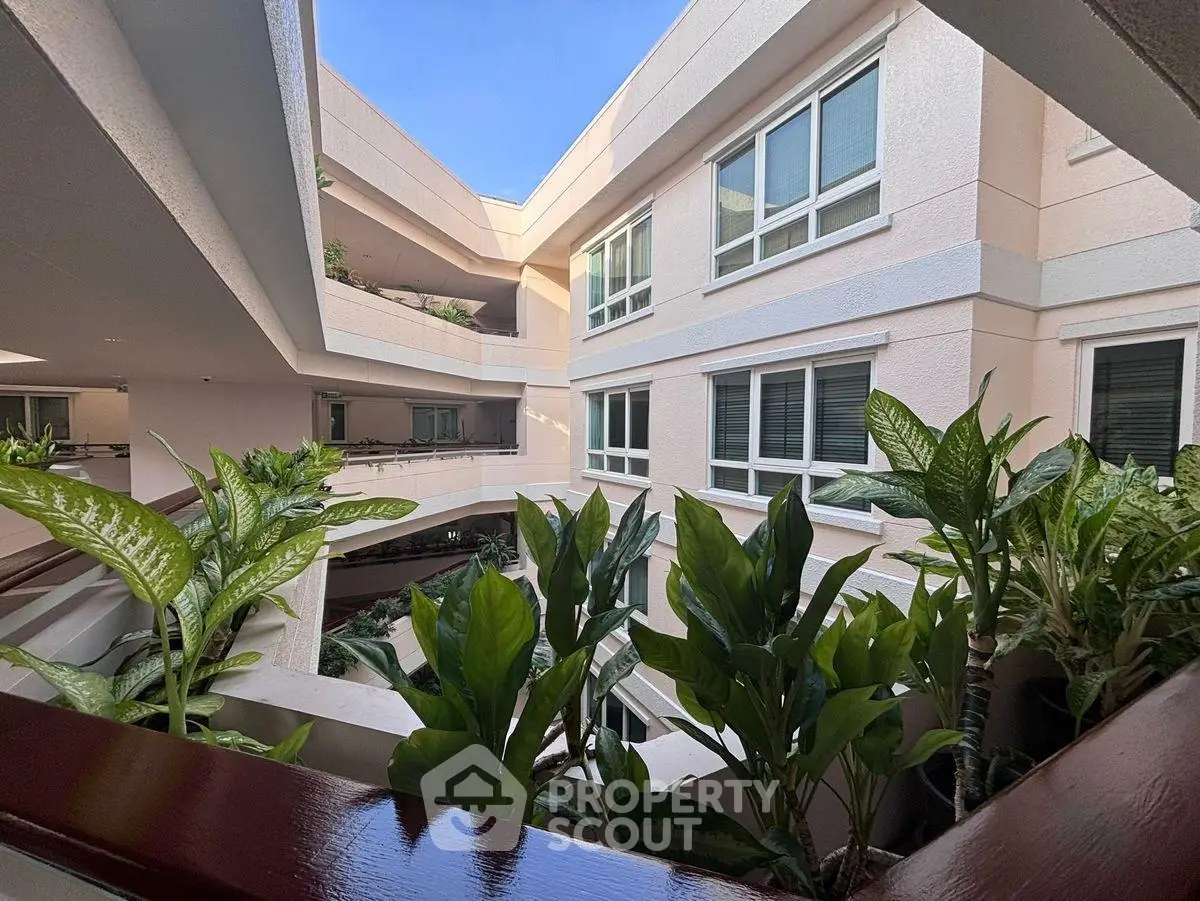 Modern apartment building with lush greenery and open courtyard view.