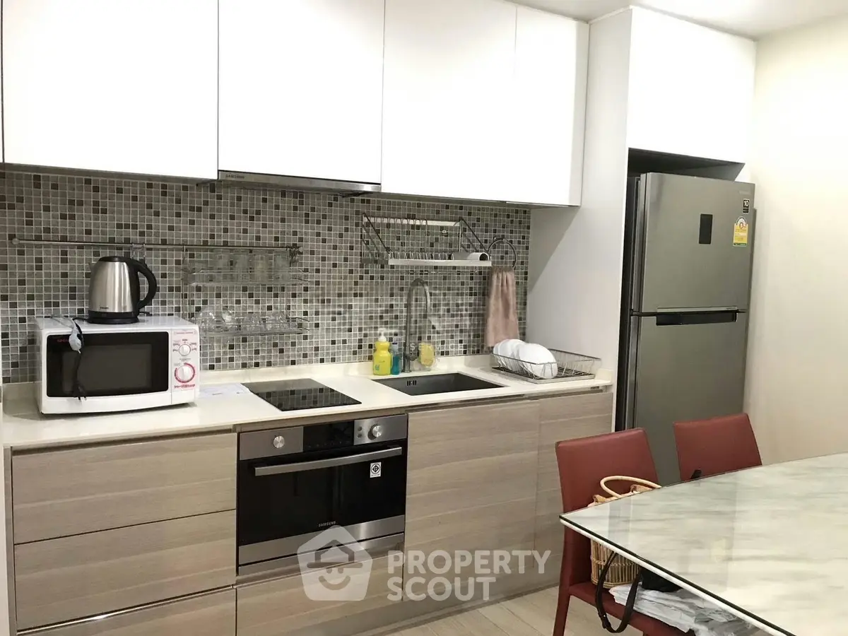 Modern kitchen with sleek cabinetry, built-in oven, and stylish backsplash.