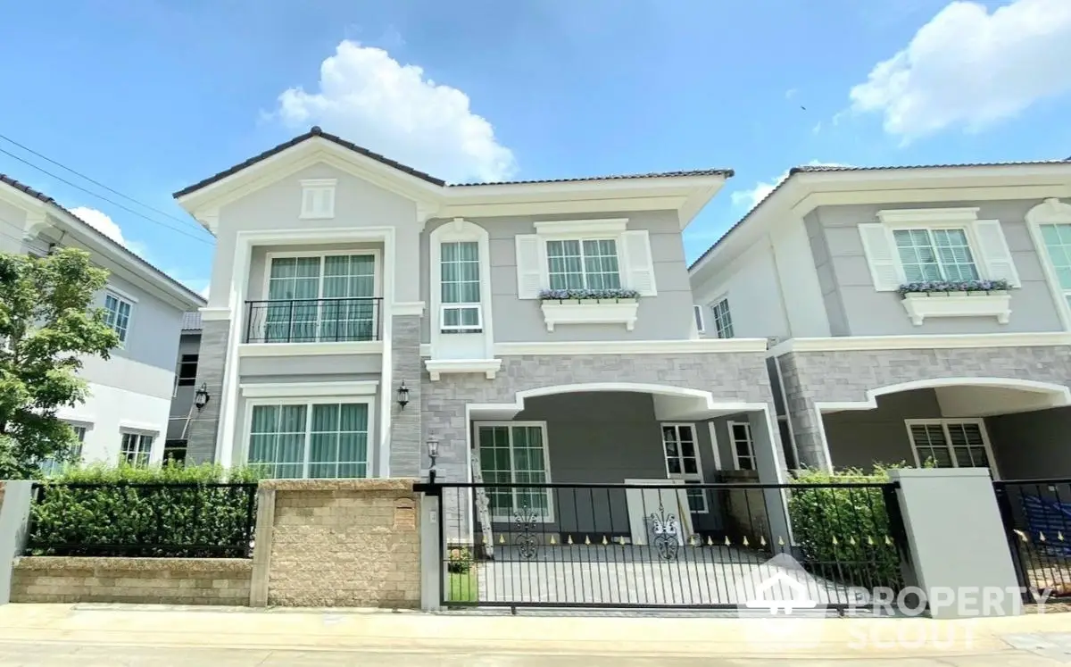 Elegant two-story house with modern facade and gated entrance in sunny neighborhood.