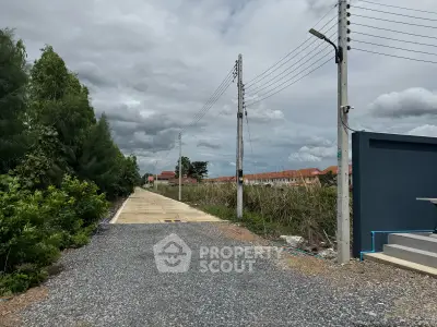 Scenic real estate plot with gravel road and lush greenery, ideal for development.