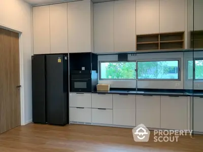 Modern kitchen with sleek cabinetry and integrated appliances, complemented by wooden flooring and ample natural light.