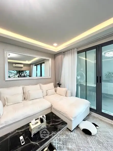 Luxurious living room with elegant white sofa and large mirror, featuring a modern design and ample natural light.