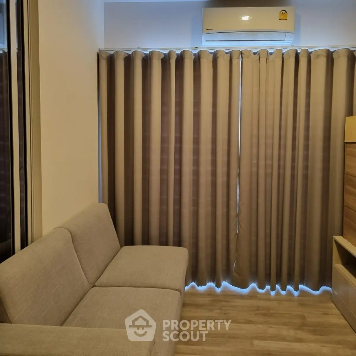 Cozy living room with modern sofa and air conditioning, perfect for relaxation.