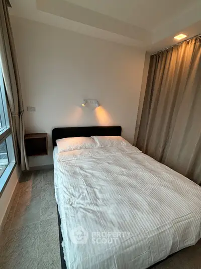 Cozy bedroom with modern design and ample natural light, featuring a comfortable bed and elegant curtains.