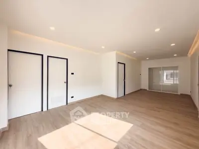 Spacious modern living room with wooden flooring and ample natural light