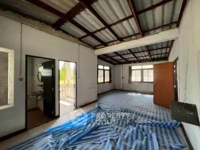 Spacious room with large windows and striped flooring, ideal for renovation.