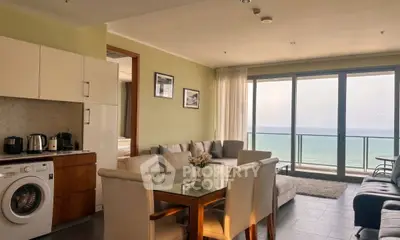 Spacious living room with ocean view, modern furniture, and open kitchen layout in a luxury apartment.
