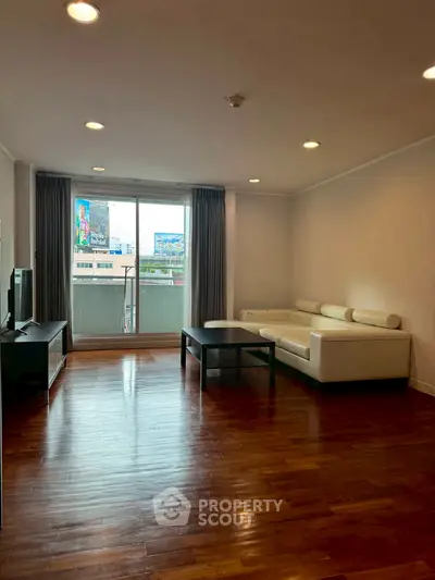 Spacious living room with modern sofa and balcony view in urban apartment.