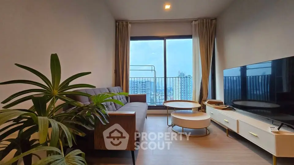 Modern living room with large window and city view, featuring stylish furniture and decor.