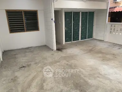 Spacious concrete patio area with sliding glass doors and louvered window, ideal for outdoor activities.