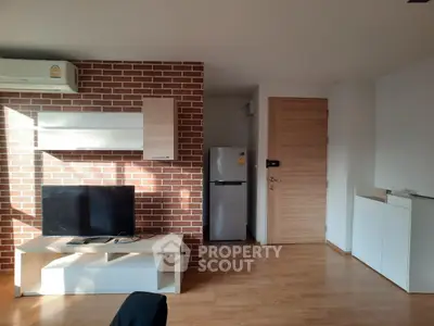 Modern living room with brick accent wall, TV unit, and sleek wooden flooring.