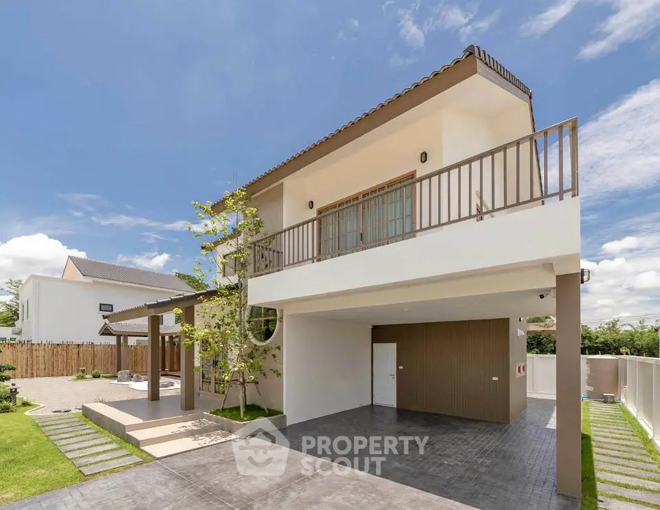 Modern two-story house with spacious balcony and landscaped front yard under clear blue sky.