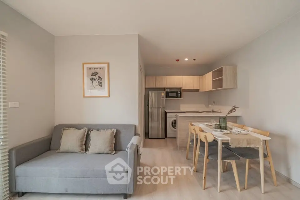 Modern open-plan living room with cozy sofa and dining area, featuring a compact kitchen with stainless steel appliances.