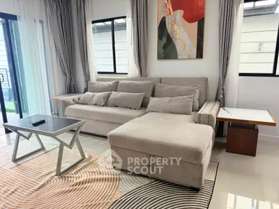 Modern living room with stylish sofa and abstract art, featuring natural light and elegant decor.