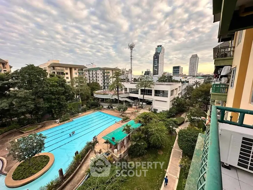 Stunning urban view with pool and lush greenery from a high-rise balcony.