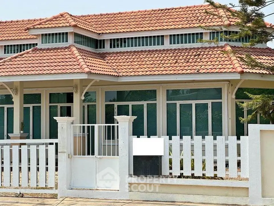 Charming single-story house with red tile roof and white picket fence