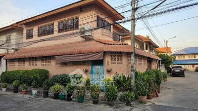 Charming two-story house with lush potted plants and unique architectural design in a serene neighborhood.