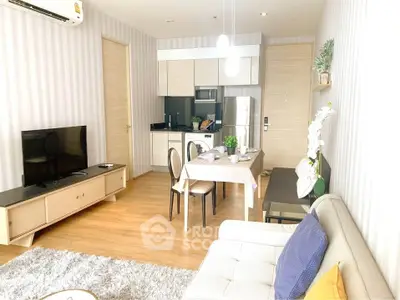 Modern open-layout living room with kitchen, featuring stylish furniture and natural light.
