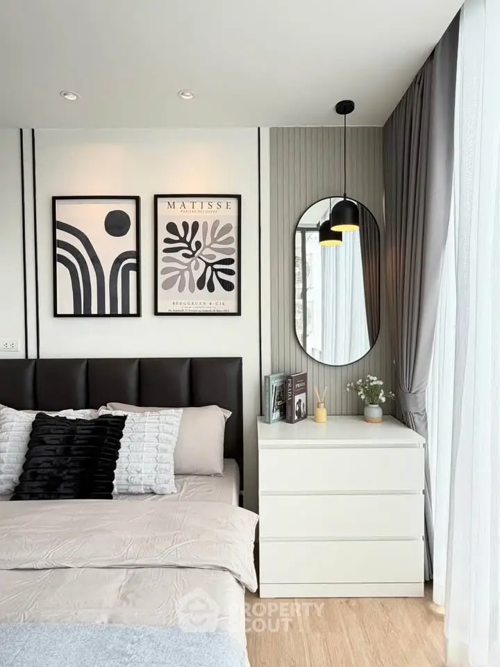 Modern bedroom with stylish decor, featuring elegant wall art, a sleek dresser, and floor-to-ceiling curtains.
