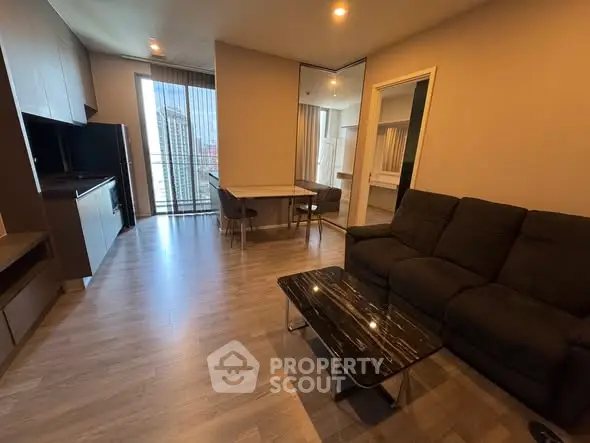 Modern living room with sleek furniture and city view from large window.