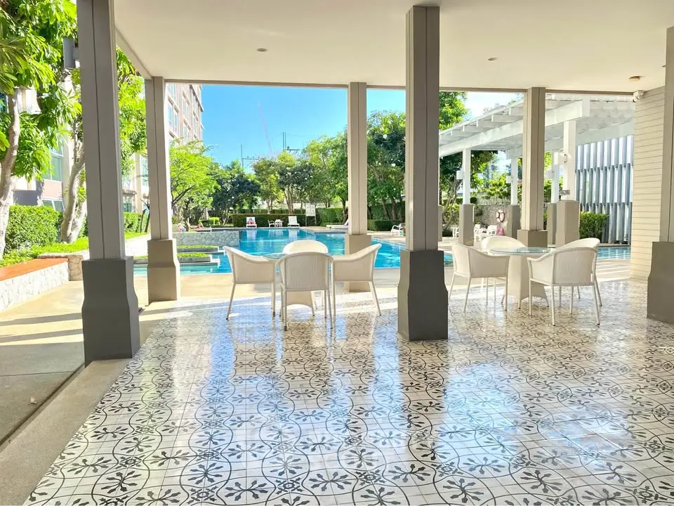 Luxurious poolside seating area with elegant tile flooring and lush greenery.