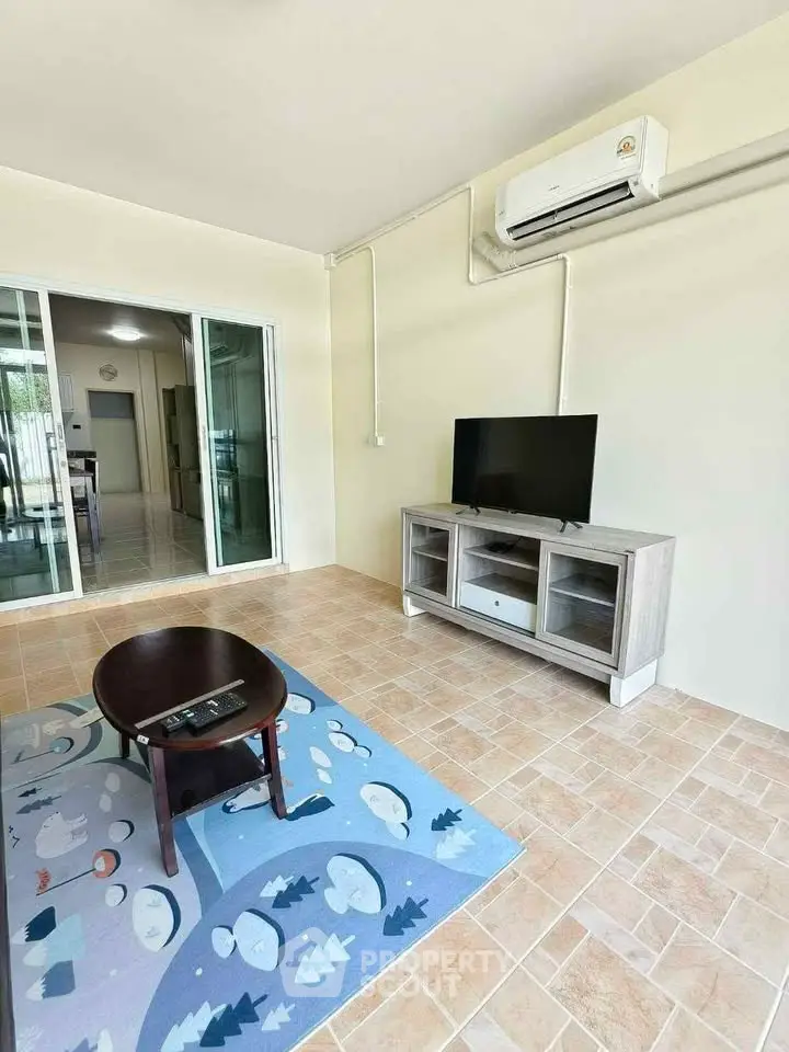 Spacious living room with modern decor and air conditioning, featuring a cozy TV setup and stylish flooring.