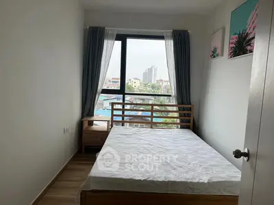 Cozy bedroom with large window offering city view, featuring wooden bed frame and modern decor.