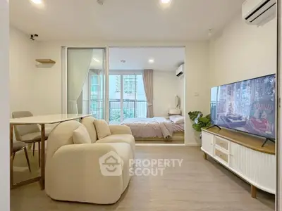 Modern open-plan living room with cozy seating and bedroom view