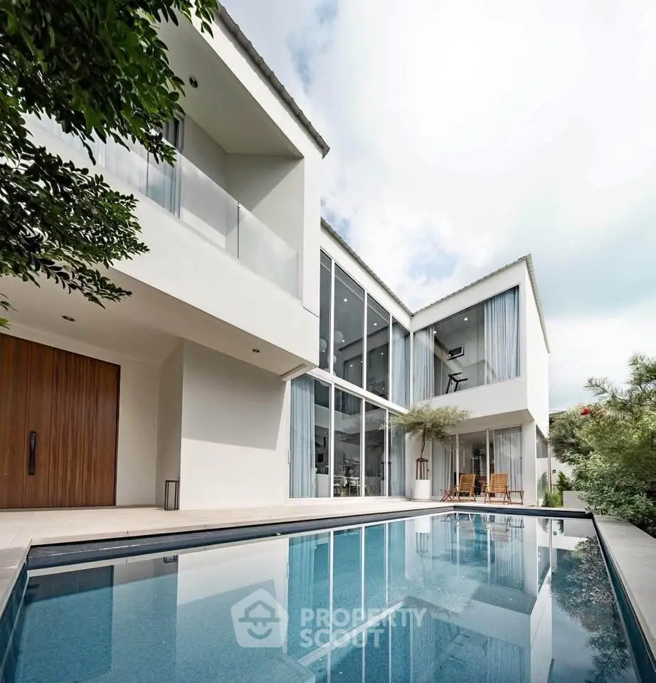Luxurious modern home with stunning pool and expansive glass windows.