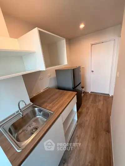 Modern kitchen with sleek design, featuring stainless steel sink and compact fridge, perfect for urban living.