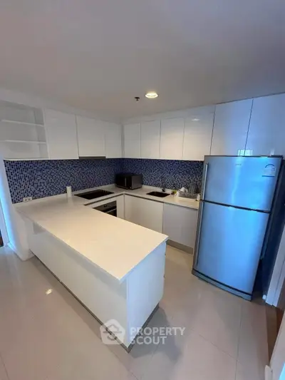 Modern kitchen with sleek white cabinetry and stainless steel appliances in a stylish open layout.