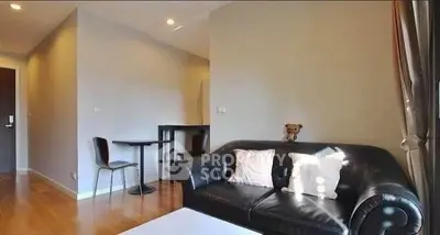 Modern living room with black leather sofa and wooden flooring