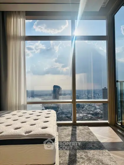 Luxurious bedroom with stunning city view through large windows, featuring elegant decor and natural light.