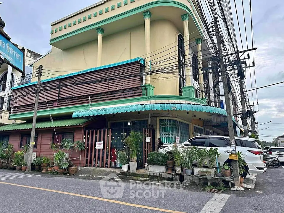 Charming corner building with unique architectural design and lush greenery, perfect for business or residence.
