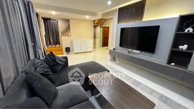 Modern living room with sleek design, large TV, and comfortable seating in a stylish home.