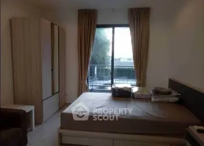 Cozy bedroom with large window and balcony access, featuring modern furniture and serene views.