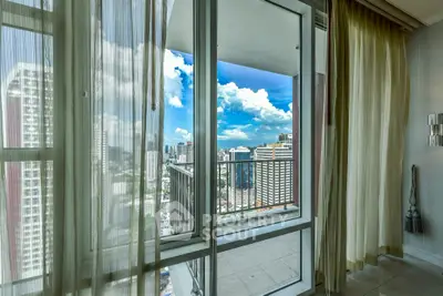 Stunning city view from modern apartment balcony with glass doors and elegant curtains.