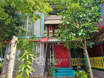 Vibrant multicolored house exterior with lush greenery and unique architectural design.