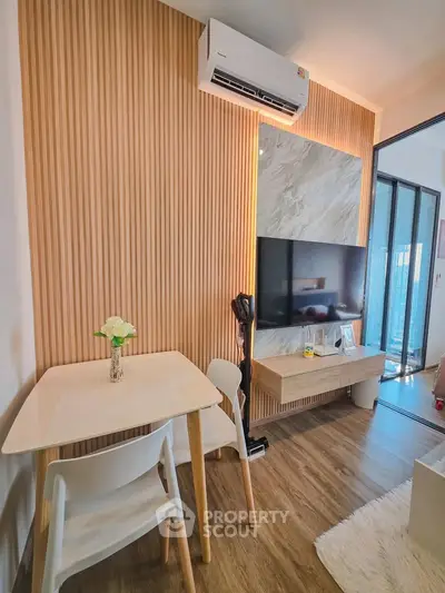 Modern living room with stylish wood paneling and sleek furniture, featuring a mounted TV and air conditioning.