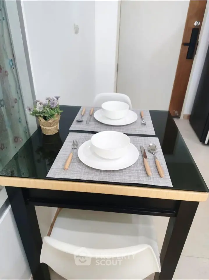 Modern dining area with sleek black table and elegant place settings in a cozy apartment.